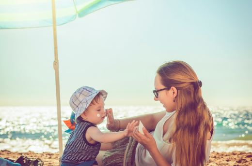 Woman applying sunscreen to child on the beach